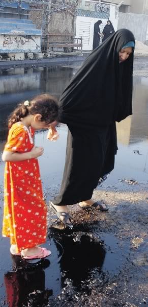 An Iraqi  girl is helped across spilled oil in Baghdad on Wednesday.